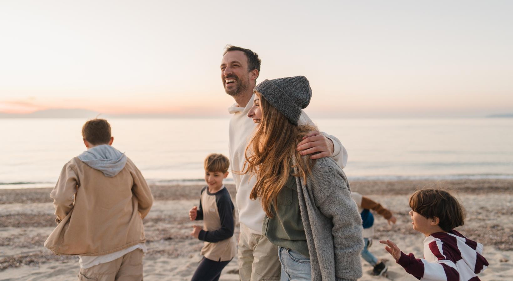 a man and woman holding hands with children on a beach